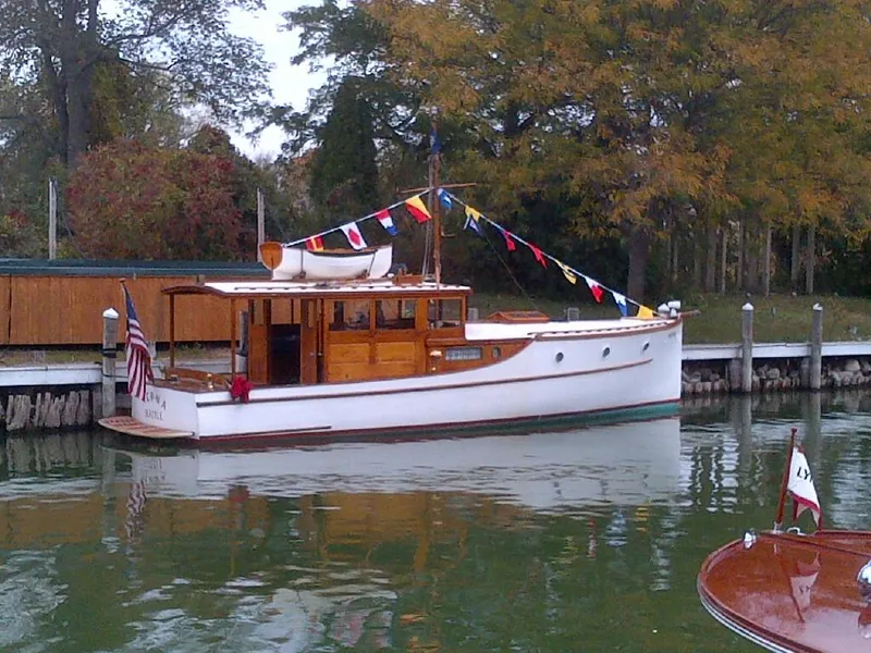 Slide: The Image of 1930 Blanchard Lake Union Dreamboat docked, adorned with colorful flags, surrounded by autumn trees. - 3