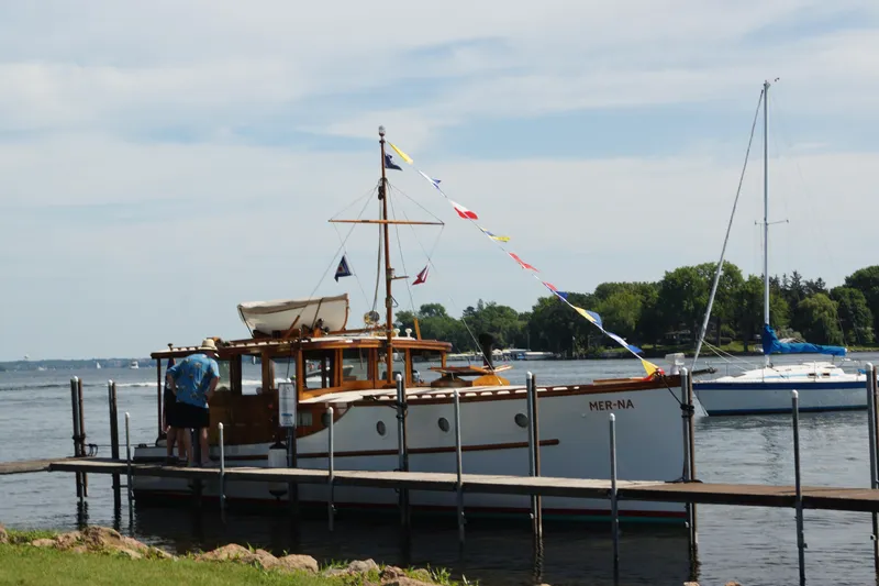 Slide: The Image of 1930 Blanchard Lake Union Dreamboat docked, adorned with colorful flags, on a sunny day. - 5