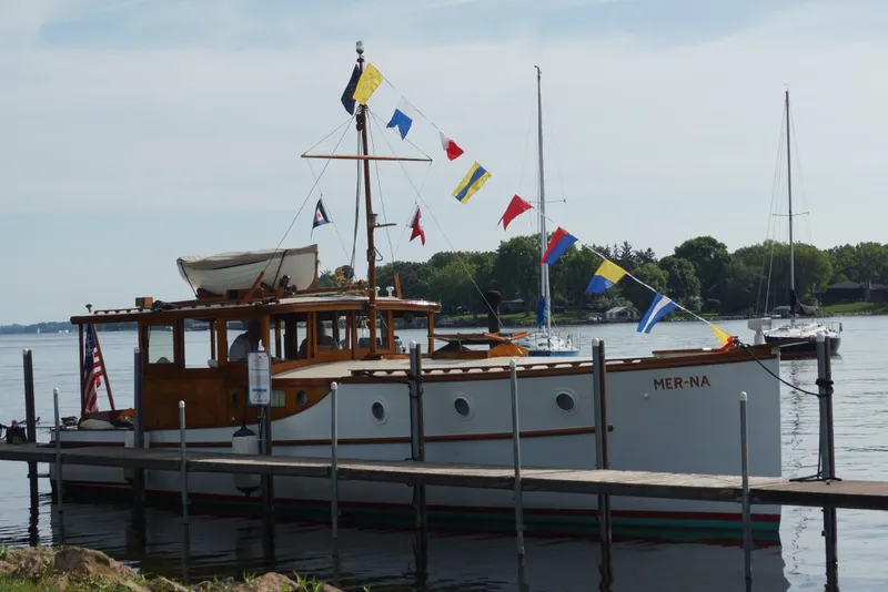 Slide: The Image of 1930 Blanchard Lake Union Dreamboat docked, adorned with colorful flags, serene water backdrop. - 6