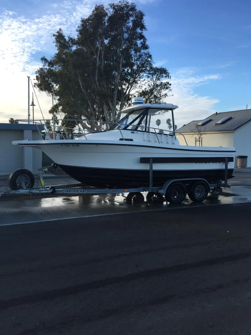 Slide: The Image of 2003 Trophy 2052 Walkaround boat on a trailer, parked near houses and trees. - 1