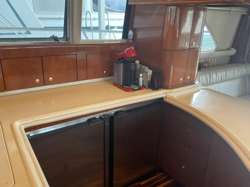 Slide: The Image of 1999 Sea Ray 560 Sedan Bridge yacht interior with wooden cabinets and kitchenette. - 11