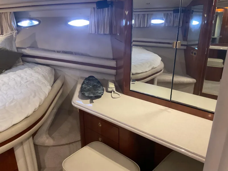 Slide: The Image of 1999 Sea Ray 560 Sedan Bridge cabin interior with bed, mirror, and wooden cabinetry. - 14