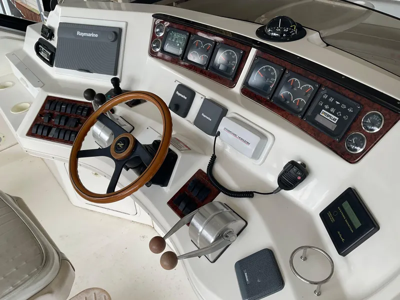 Slide: The Image of 1999 Sea Ray 560 Sedan Bridge helm with gauges, controls, and wooden steering wheel. - 19