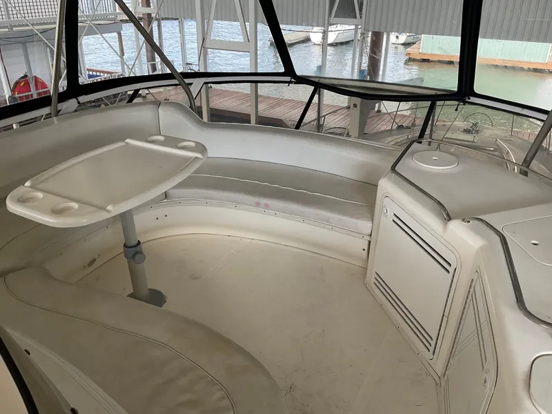 Slide: The Image of 1999 Sea Ray 560 Sedan Bridge interior with seating and table, docked at marina. - 20
