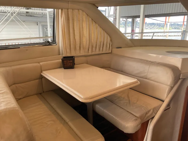 Slide: The Image of 1999 Sea Ray 560 Sedan Bridge interior dining area with beige seating and table. - 9