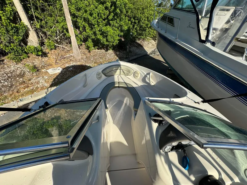Slide: The Image of 2005 Sea Ray 180 Sport boat interior with open windshield, docked near trees. - 23