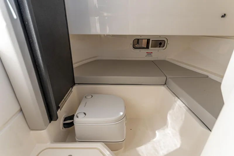 Slide: The Image of 2021 Sea Ray SDX 250 cabin interior with compact toilet and seating area. - 29