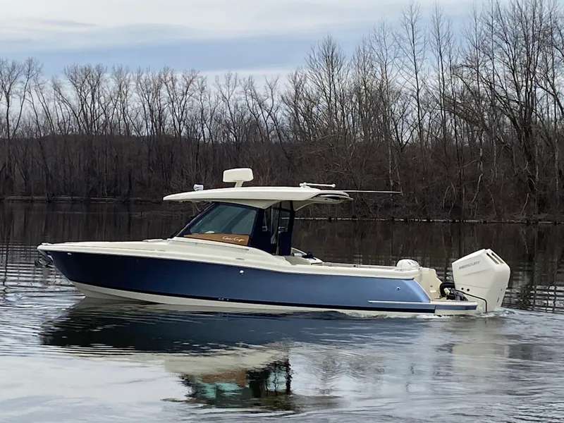 Slide: The Image of 2024 Chris-Craft Calypso 32 boat on calm water with trees in the background. - 2