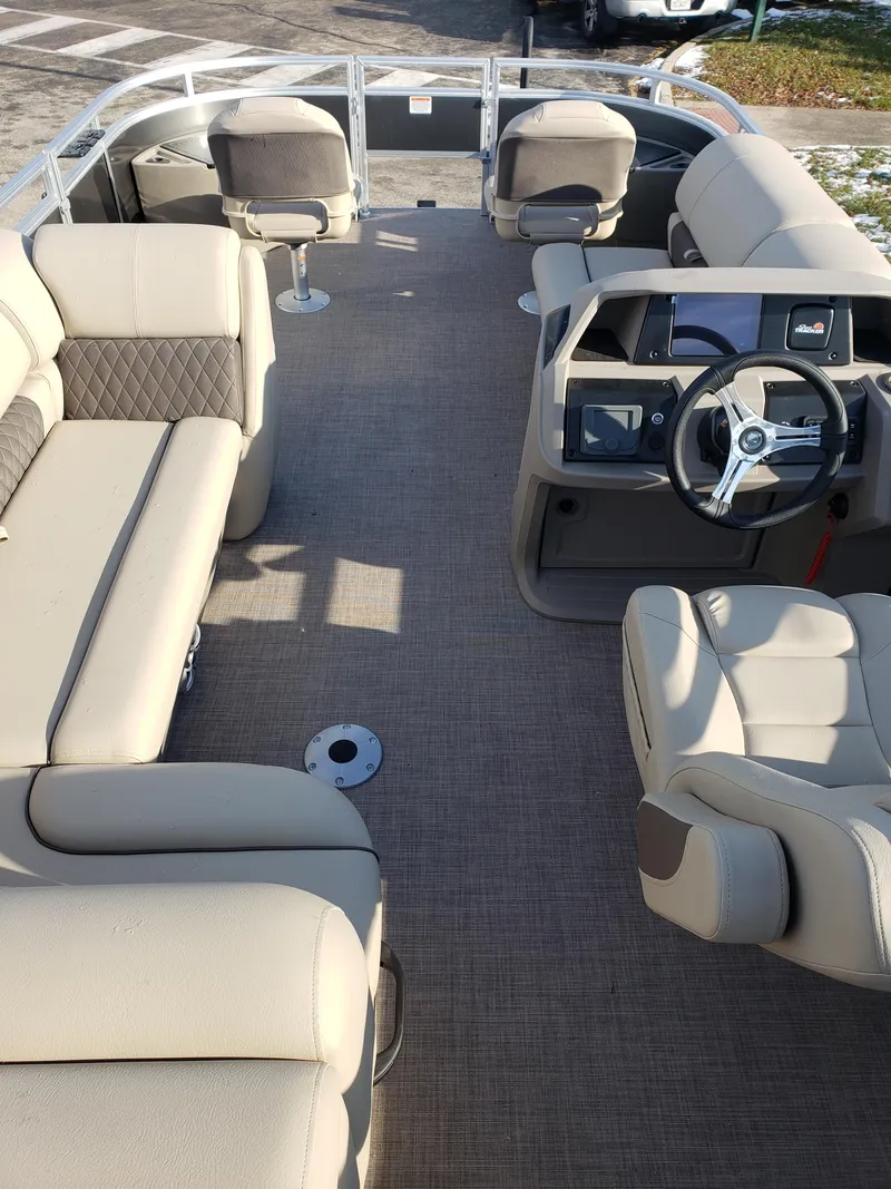 Slide: The Image of 2024 Sun Tracker Fishin' Barge 20 DLX interior with beige seating and steering console. - 2