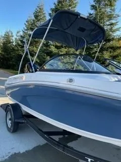 Slide: The Image of 2024 Tahoe 185 S boat with canopy on trailer, parked outdoors. - 2