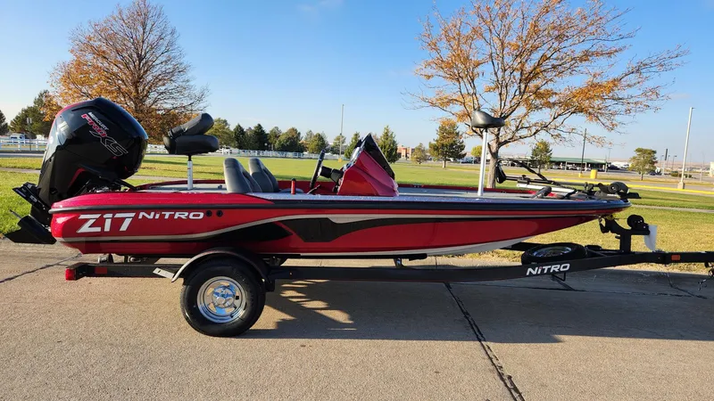 Slide: The Image of 2024 Nitro Z17 fishing boat on trailer, red and black design, parked outdoors. - 0