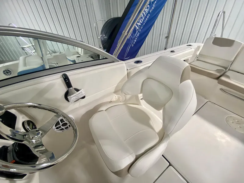 Slide: The Image of 2024 Robalo R207 Dual Console boat interior with white seating and steering wheel. - 18