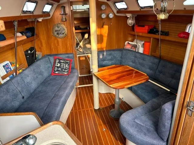 Slide: The Image of Interior of a 1998 Catalina 320 yacht with wooden flooring and blue upholstery. - 16