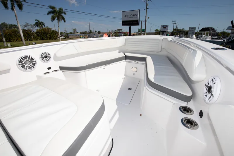 Slide: The Image of 2024 Edgewater 340CC boat interior with white and gray seating, cup holders, and speakers. - 14