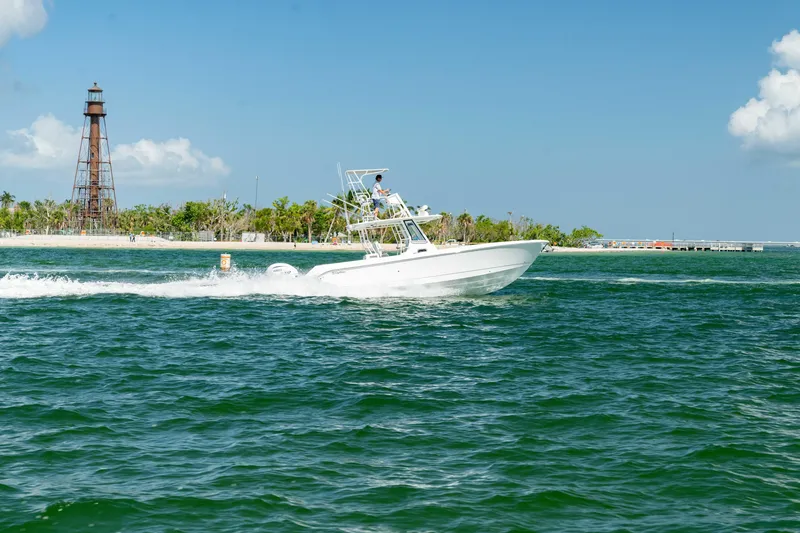 Slide: The Image of 2024 Edgewater 340CC boat cruising near a lighthouse on a sunny day. - 38