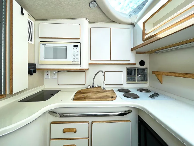 Slide: The Image of 1995 Sea Ray 370 Sedan Bridge kitchen with microwave, stove, and sink. - 3