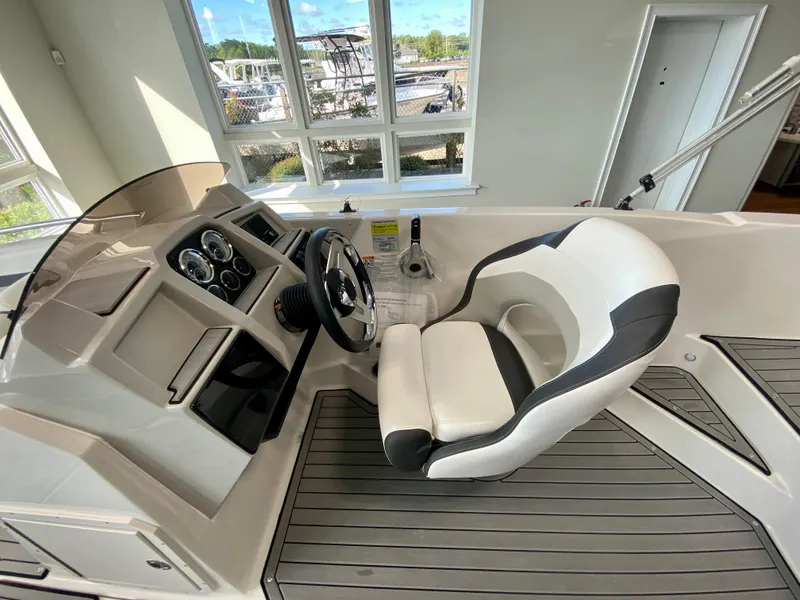 Slide: The Image of 2024 Starcraft SVX 211 Electric Blue Sport boat cockpit with steering wheel and captain's chair. - 12
