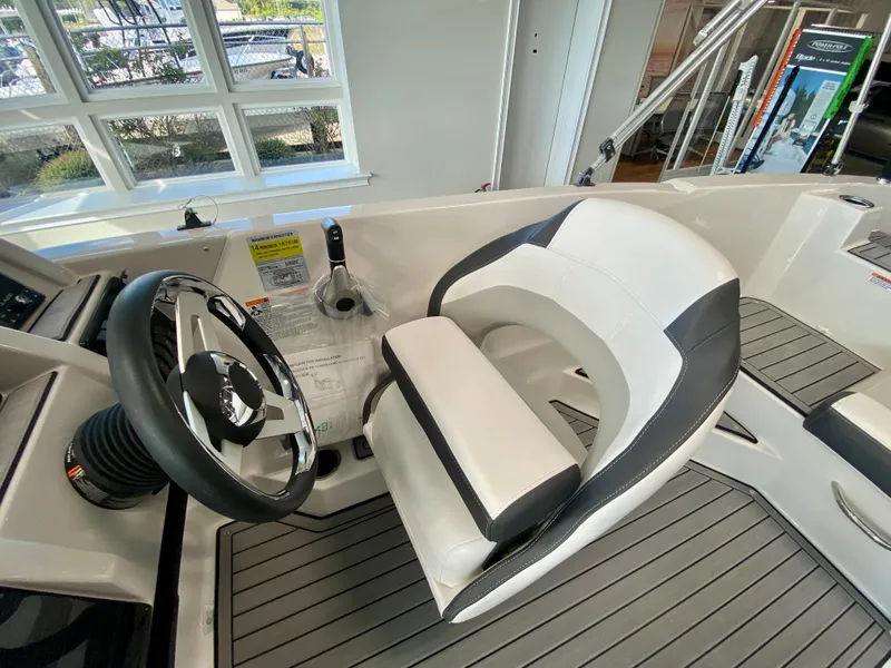 Slide: The Image of 2024 Starcraft SVX 211 Electric Blue Sport boat interior with steering wheel and captain's chair. - 13