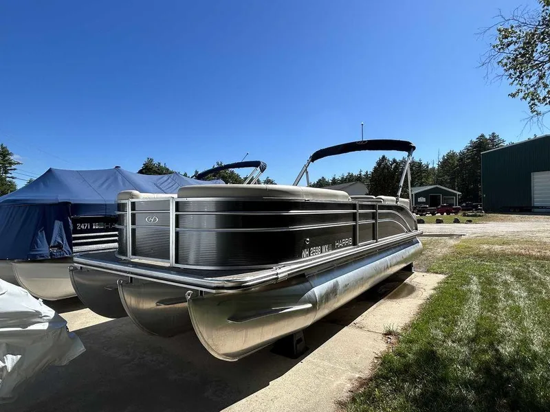Slide: The Image of 2021 Harris Cruiser 250 pontoon boat parked outdoors on a sunny day. - 4