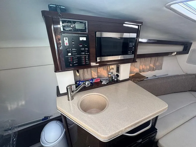 Slide: The Image of 2015 Sea Ray 260 Sundancer cabin with kitchenette, microwave, and control panel. - 10