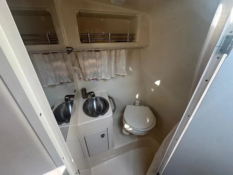 Slide: The Image of 2015 Sea Ray 260 Sundancer bathroom with sink, toilet, and storage shelves. - 12