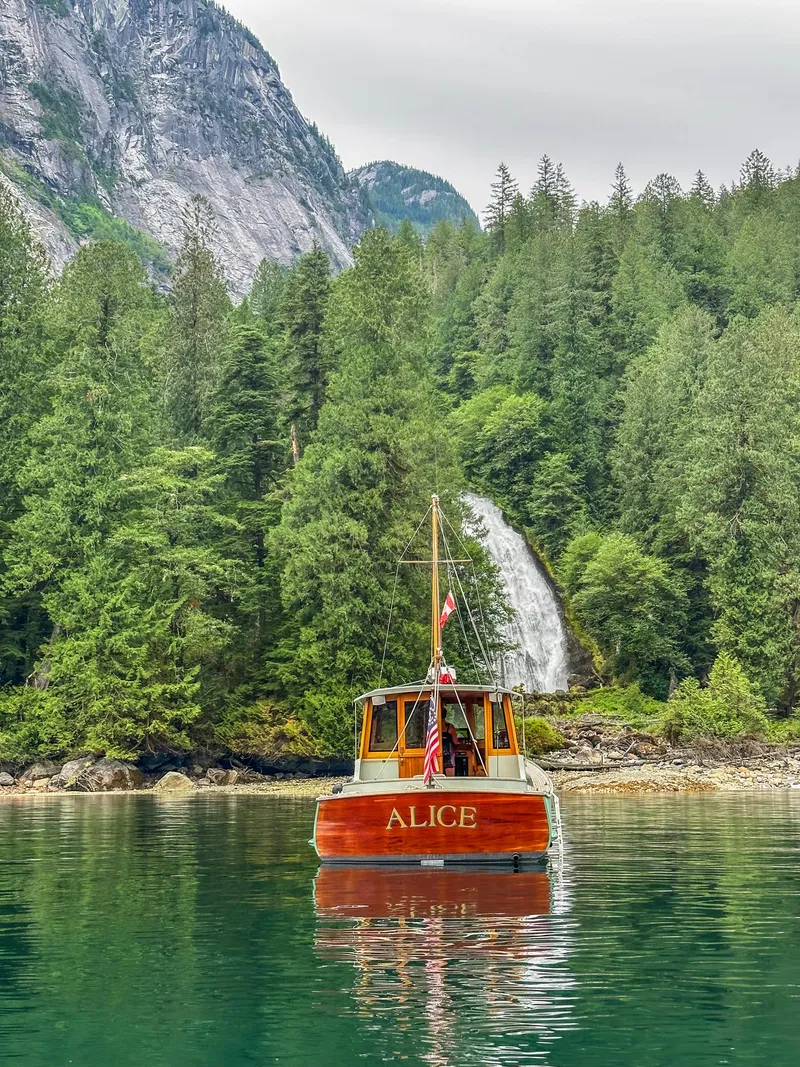 Slide: The Image of Custom 2009 Gartside Downeast Cruiser Alice on serene lake with waterfall and forest backdrop. - 2