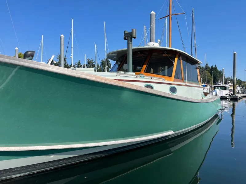 Slide: The Image of 2009 Custom Gartside Downeast Cruiser docked at marina, green hull, wooden cabin, clear sky. - 3