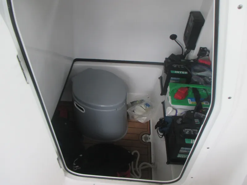 Slide: The Image of 2019 Sportsman 267 Masters boat interior storage compartment with portable toilet and batteries. - 11