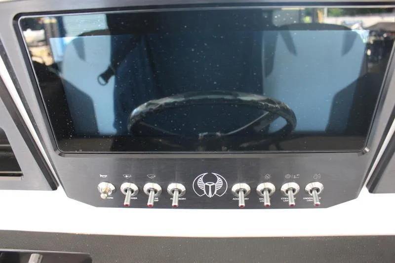 Slide: The Image of 2023 Scarab 255 ID boat dashboard with control switches and steering wheel. - 8