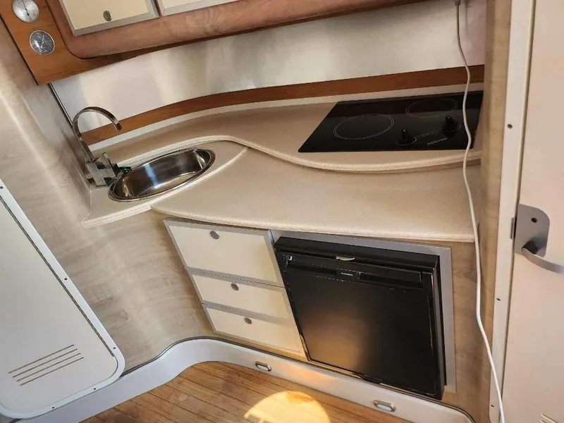 Slide: The Image of Compact kitchen area in 2018 Pronautica 1260 Super Sport boat with sink, stove, and mini-fridge. - 7