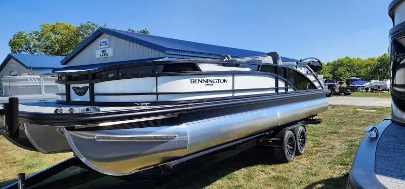 Slide: The Image of 2024 Bennington 25 RTSB pontoon boat on a trailer, parked on grass. - 3