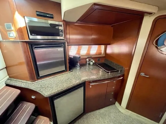 Slide: The Image of 2007 Sea Ray 38 Sundancer kitchen with microwave, fridge, and wooden cabinetry. - 17