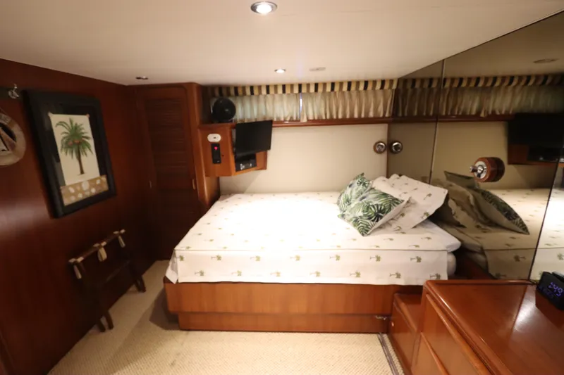 Slide: The Image of 1991 Viking Motor Yacht bedroom with wooden decor, bed, and mirrored wall. - 24