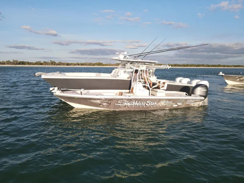 Slide: The Image of 2014 Pathfinder 2600 HPS boat on water, clear sky, fishing rods visible. - 1