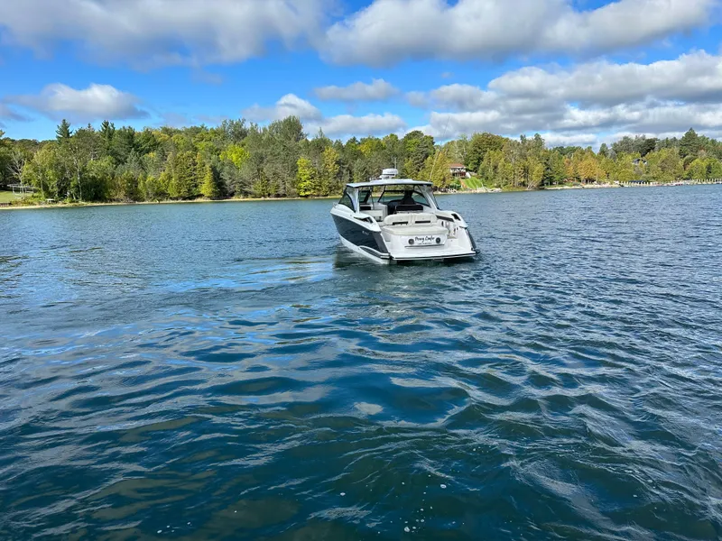 Slide: The Image of 2015 Cobalt A40 boat cruising on a scenic lake with a forested shoreline. - 14