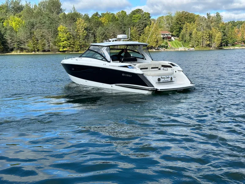 Slide: The Image of 2015 Cobalt A40 boat cruising on a scenic lake with forested shoreline. - 16