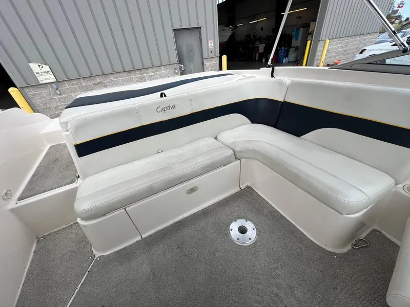 Slide: The Image of 2002 Rinker 212 Captiva Bowrider interior seating area with white and navy upholstery. - 3