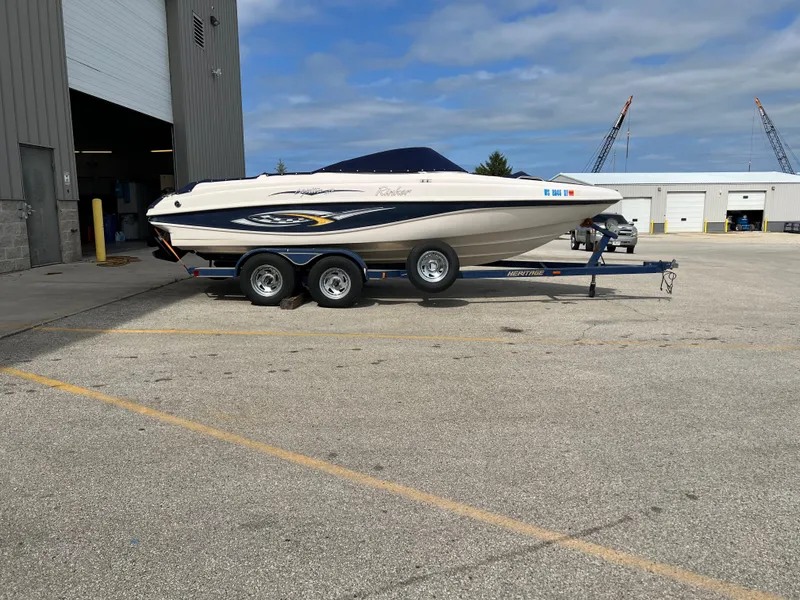 Slide: The Image of 2002 Rinker 212 Captiva Bowrider on a trailer outside a warehouse. - 8