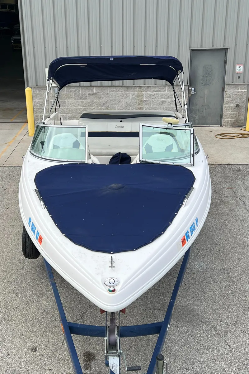 Slide: The Image of 2002 Rinker 212 Captiva Bowrider boat with blue cover in storage. - 9