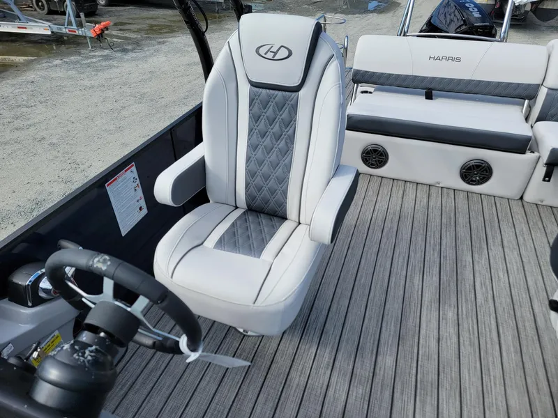 Slide: The Image of 2024 Harris Sunliner 230 Sport boat interior with captain's chair and steering wheel. - 12