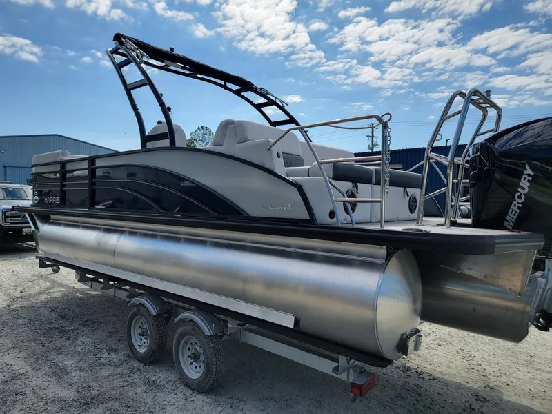 Slide: The Image of 2024 Harris Sunliner 230 Sport pontoon boat on trailer under blue sky. - 4