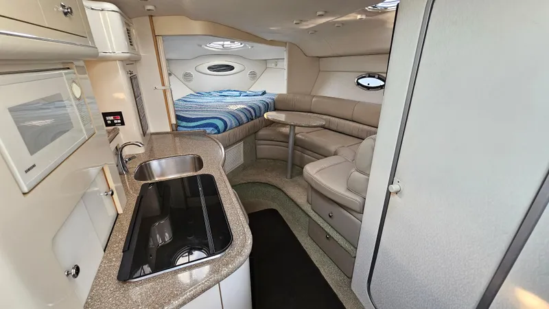 Slide: The Image of 1999 Maxum 3000 SCR boat interior with kitchen, seating area, and bed. - 15