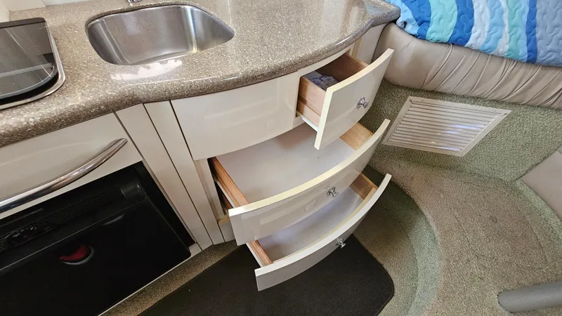 Slide: The Image of 1999 Maxum 3000 SCR boat interior with open kitchen drawers and sink. - 25