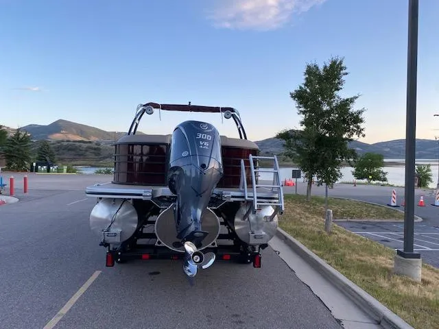 Slide: The Image of 2024 Bennington 24LXSRA pontoon boat with Yamaha 300 V6 engine on trailer by a lake. - 4