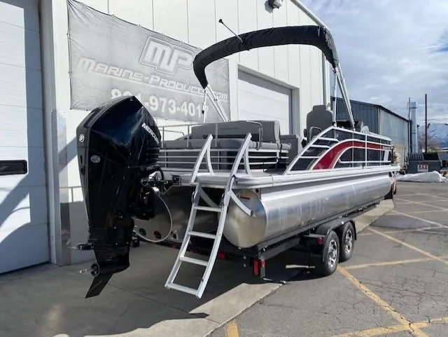 Slide: The Image of 2023 Bennington 25LSB pontoon boat on trailer, parked outside Marine Products store. - 3