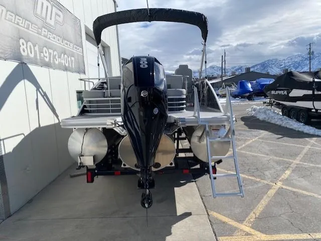 Slide: The Image of 2023 Bennington 25LSB pontoon boat with outboard motor and ladder, parked outside a marine products store. - 4