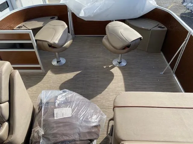Slide: The Image of 2023 Bennington 22LFAPG pontoon boat interior with beige seating and wood accents. - 6