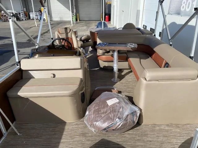 Slide: The Image of 2023 Bennington 22LFAPG pontoon boat interior with beige seating and steering console. - 8