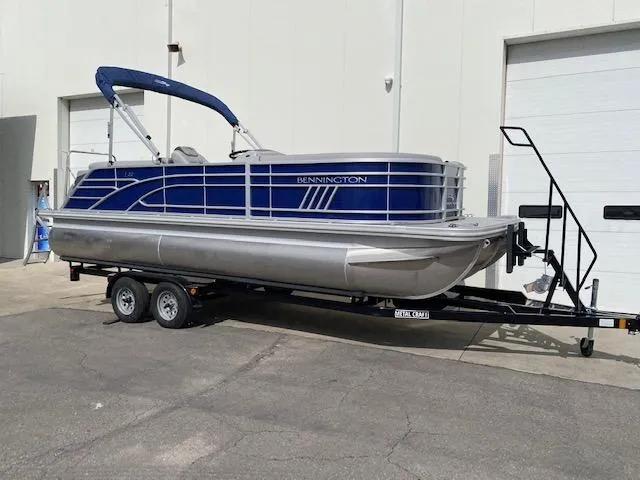 Slide: The Image of 2023 Bennington 22LFB pontoon boat on a trailer outside a warehouse. - 1