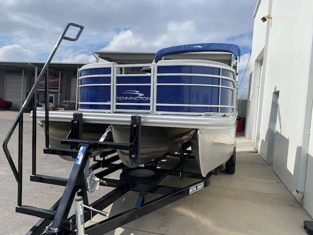 Slide: The Image of 2023 Bennington 22LFB pontoon boat on a trailer, parked outdoors. - 2